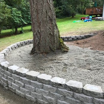 Stone retaining wall border built around large tree